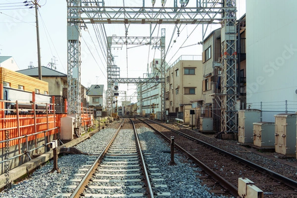 Fototapeta Urban railway track passing through residential building in Japan