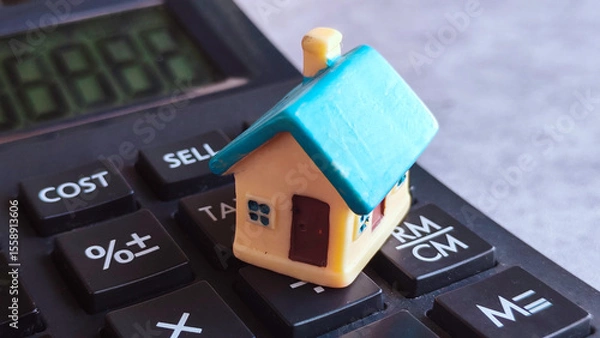 Fototapeta Miniature House on Calculator with Financial Keys, Representing Real Estate Investment and Property Costs