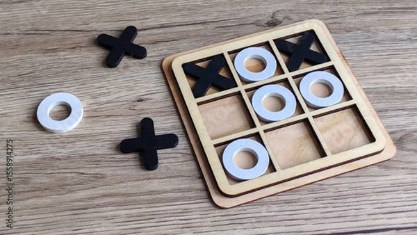 Fototapeta Wooden Tic-Tac-Toe Game with X and O Pieces on Table, Symbolizing Strategy, Games, and Competition