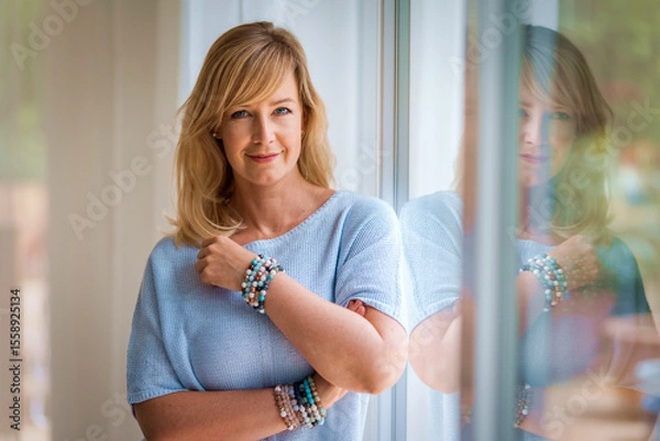 Obraz Shot of a blond haired woman standing by the window