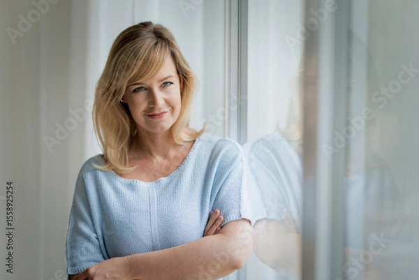 Obraz Shot of a blond haired woman standing by the window