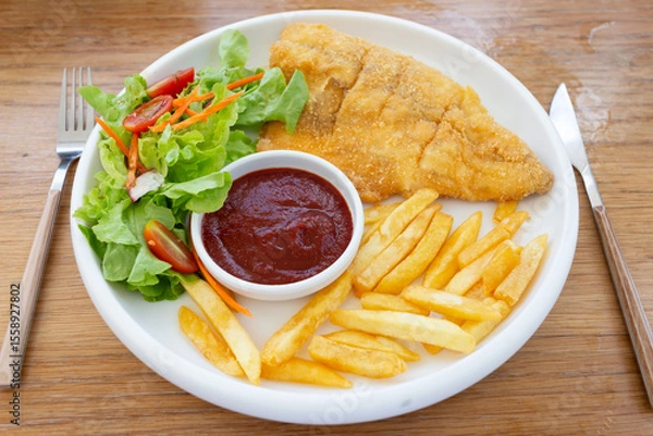 Obraz Fish steak with vegetable salad and french fries on a plate, top view