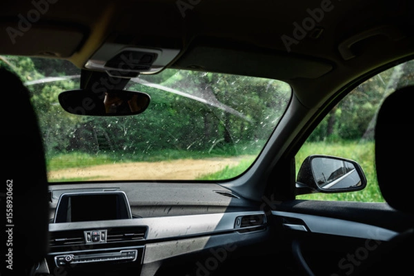 Fototapeta Smeared and dirty front windshield of a vehicle after hitting bugs.