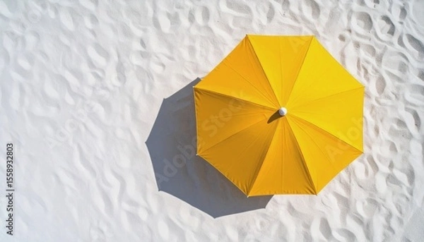 Fototapeta  Top view of a bright yellow beach umbrella casting a soft circular