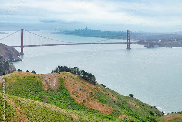 Fototapeta Iconic view of the Golden Gate Bridge stretching across the blue waters of the San Francisco Bay, seen from a green cliffside near Kirby Cove. A timeless symbol of California travel and nature