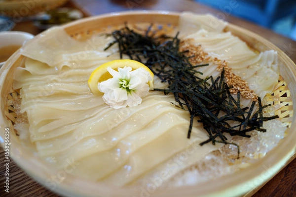 Obraz Glossy Cold Udon Noodles in a Bamboo Basket with Ice and Nori – Japanese Cuisine Close-Up