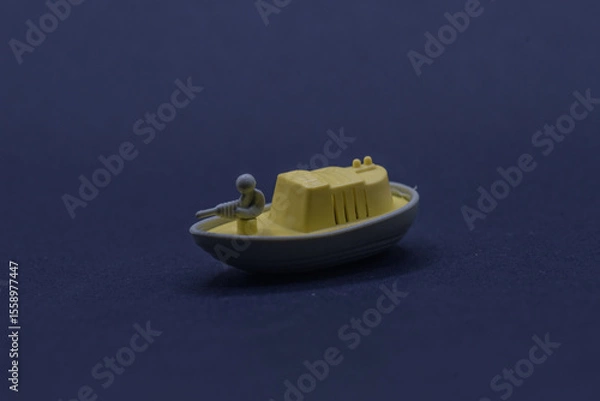 Obraz a small toy boat equipped with soldiers holding weapons on the front deck.