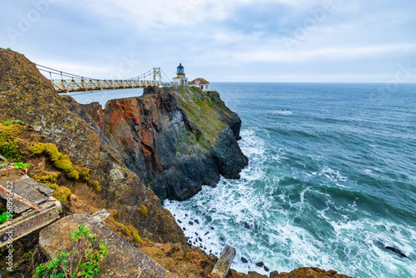 Fototapeta Point Bonita Lighthouse on rugged cliffs above the Pacific Ocean in Marin Headlands, California. Iconic coastal landmark near Highway 1, with crashing waves and dramatic sea views