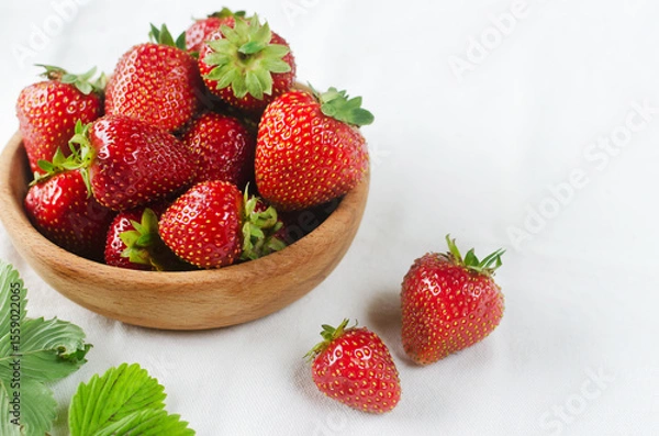 Fototapeta Ripe red strawberries in a ceramic bowl on a white background. Concept of summer berry harvest. Horizontal orientation. Selective focus. Copy space.