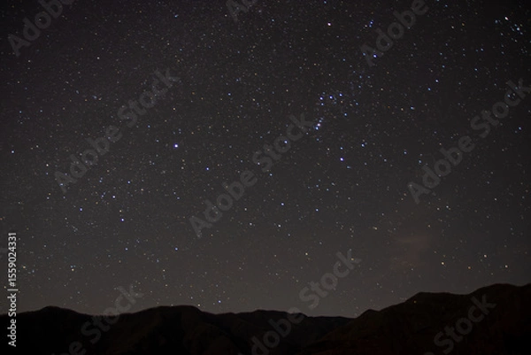 Obraz 埼玉県秩父市の山並みに浮かぶ冬の夜空と星空、オリオン座が輝く静寂な風景。澄んだ空気の中、山の稜線がシルエットとなり、自然と宇宙の神秘を感じさせる夜の風景。

