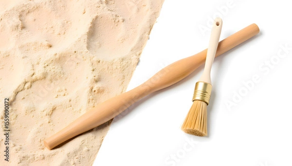 Fototapeta Wooden rolling pin and pastry brush resting on a light-colored flour surface, showcasing baking tools for culinary enthusiasts and home cooks in a kitchen setting