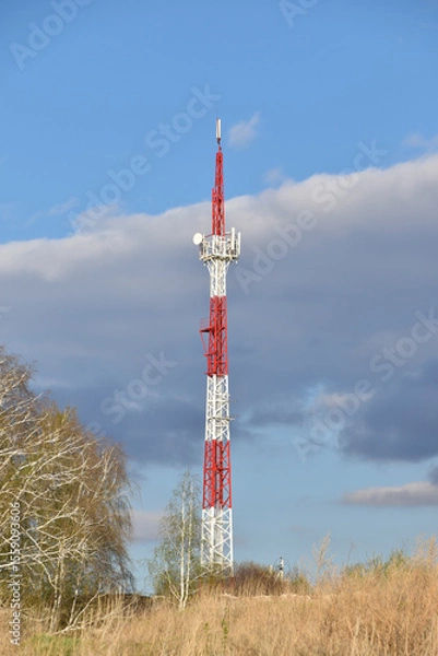 Fototapeta The communication tower is painted in red and white. A communications tower in rural areas.