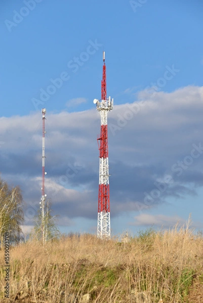 Fototapeta The communication tower is painted in red and white. A communications tower in rural areas.
