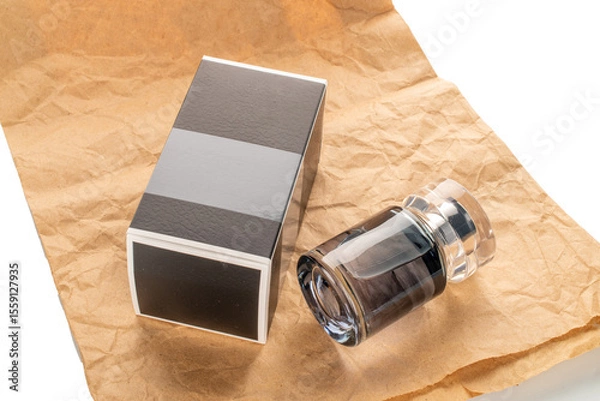 Fototapeta One bottle of perfume and paper packaging on kraft paper isolated on white background, close-up.