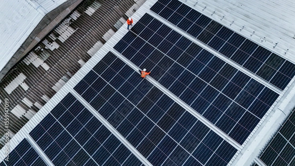 Fototapeta Solar power technician inspecting rooftop solar panels, performing maintenance and installation of renewable energy systems for a sustainable future.