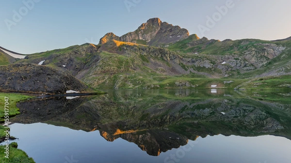 Fototapeta Mountain peak reflecting in a lake at sunrise in the pyrenees mountains.