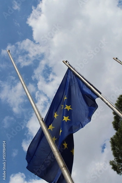 Obraz European union flag in the wind on a blue cloudy sky background 