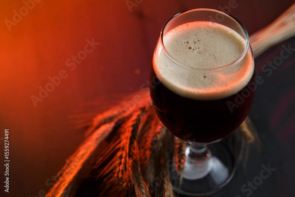 Fototapeta Stout beer glass on wooden table with rye ears. Copy space