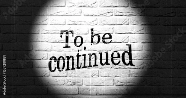Fototapeta A spotlight highlights the phrase "To be continued" on a textured brick wall