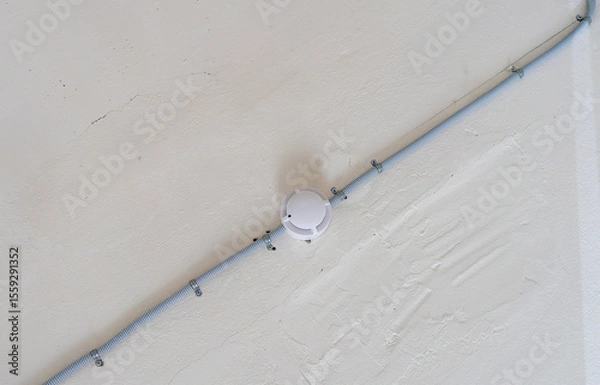 Fototapeta Installation of a fire alarm system on the ceiling.Installation of smoke detectors in the room.Fire safety.