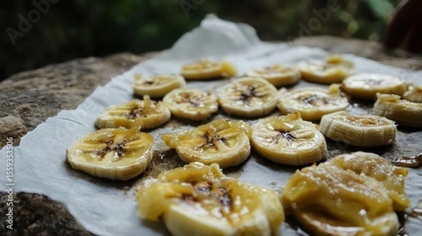 Fototapeta Sliced ripe bananas arranged on a parchment paper in natural light