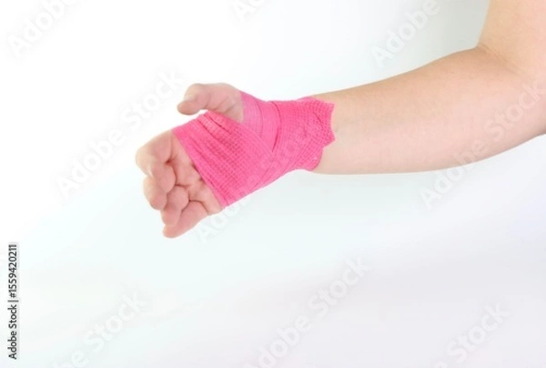 Fototapeta Woman hand with a pink cohesive bandage isolated in a white background