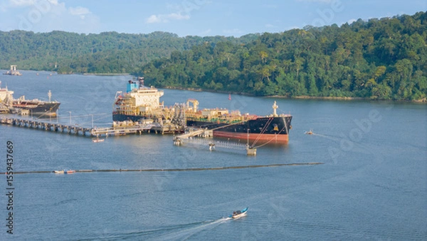 Obraz Cilacap oil tankers are moored at a busy port near Nusakambangan Island hills.
