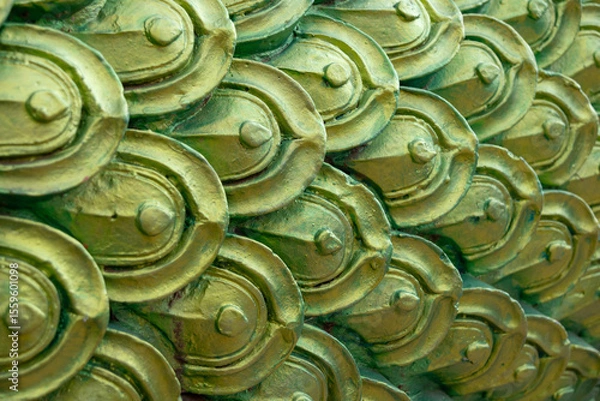 Obraz close-up of ornate, metallic green and gold scales, reminiscent of a dragon or the mythical Naga serpent in Thai art.