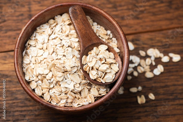 Fototapeta Rolled oats in a wooden bowl, detailed closeup view. Raw uncooked oatmeal porridge, grains