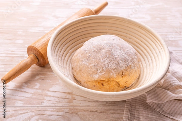Obraz Raw yeast dough with rolling pin resting and rising in a special basket