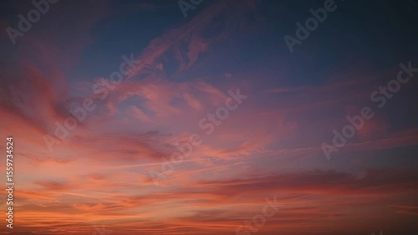 Fototapeta Magnificent sky at sunset painted in vibrant hues of orange, pink, and purple, with soft clouds drifting across the glowing horizon, creating a serene and breathtaking view of nature’s evening beauty