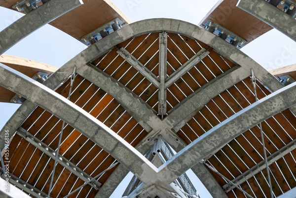 Fototapeta Detail of the top structure of the Tokaj observation tower near Malá Tŕňa, Slovakia. Steel and wood construction with visible beams, joints, and braces under clear sky.