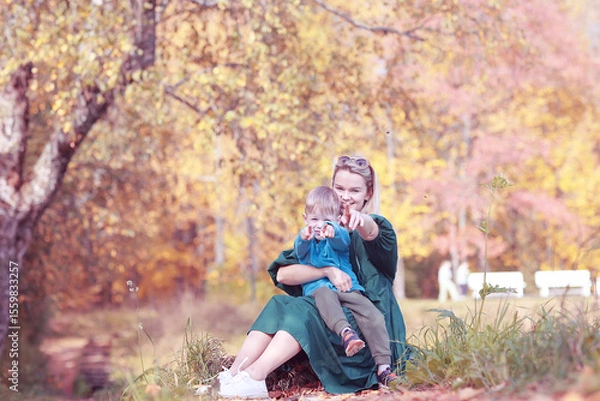 Obraz A boy and a mother hug in an autumn park against a background of yellow trees on a warm autumn day
