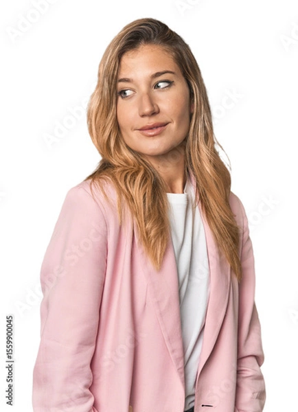 Fototapeta Young blonde in stylish pink suit looks aside smiling, cheerful and pleasant.