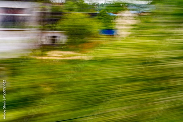 Obraz Dynamic motion blur view from high-speed train window: Green landscape, trees & fields rush past at high speed