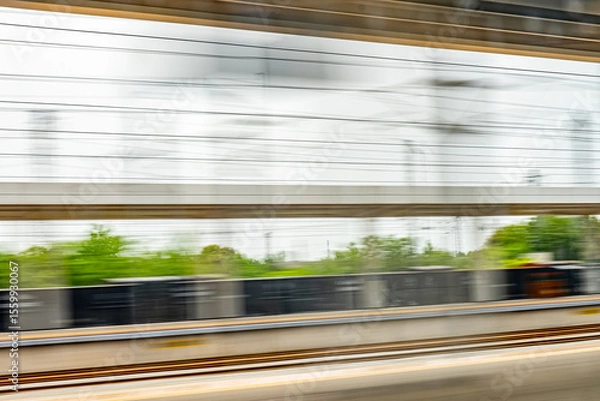 Obraz Dynamic motion blur view from high-speed train window: Green landscape, trees & fields rush past at high speed