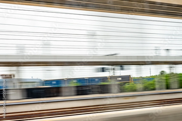 Obraz Dynamic motion blur view from high-speed train window: Green landscape, trees & fields rush past at high speed