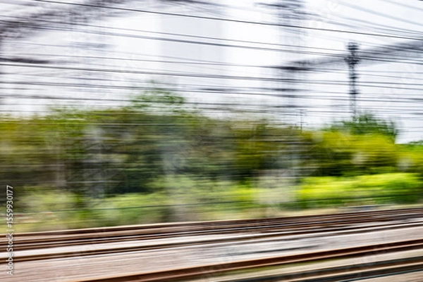 Obraz Dynamic motion blur view from high-speed train window: Green landscape, trees & fields rush past at high speed