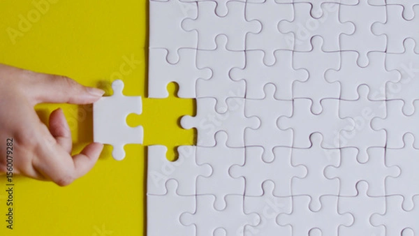 Fototapeta Hand holding the final puzzle piece to complete the business solution, symbolizing teamwork and connection