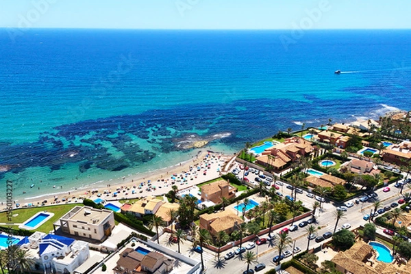 Fototapeta Aerial view beautiful coastal resort area of Cabo Roig. Crystal-clear Mediterranean Sea waters, sandy beach with sunbathing people, luxurious waterfront properties with private pools. Alicante, Spain