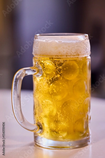 Fototapeta a pint of cold and steaming beer on a table