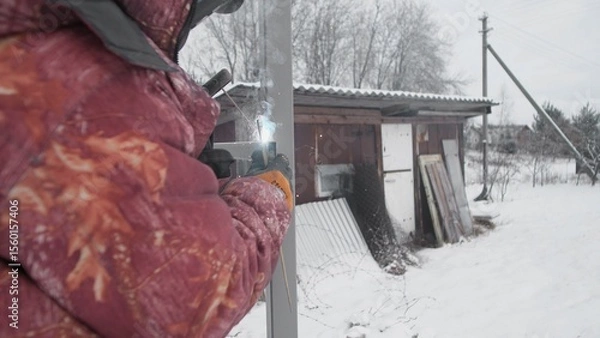 Fototapeta A beautiful snowy landscape showcases a person skillfully working with various tools near a rustic shed