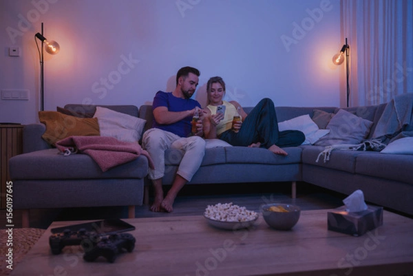 Obraz  Couple Sitting on Couch with Drinks and Smartphone During Cozy Evening at Home
