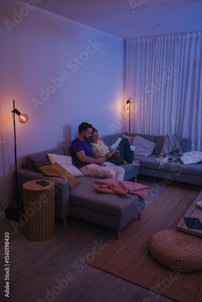 Obraz  Couple Sitting on Couch with Drinks and Smartphone During Cozy Evening at Home