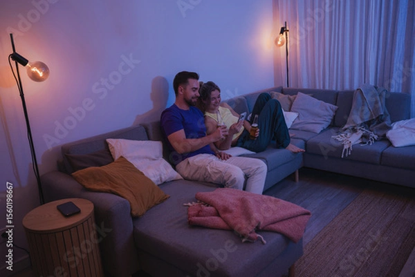 Obraz  Couple Sitting on Couch with Drinks and Smartphone During Cozy Evening at Home