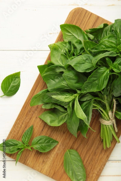 Obraz Green basil herb on cutting board on white background. Vertical photo