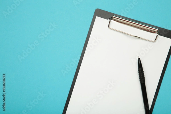 Obraz Pen and black clipboard with paper on blue background.