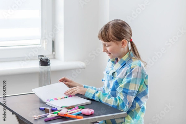 Fototapeta Smiling girl reading notes in colorful notebook