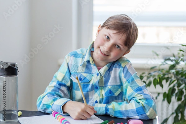 Fototapeta Smiling child doing schoolwork at desk