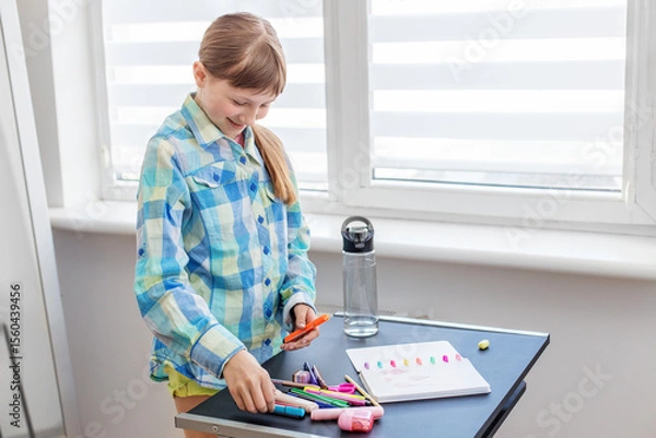 Fototapeta Smiling child organizing colorful markers at desk